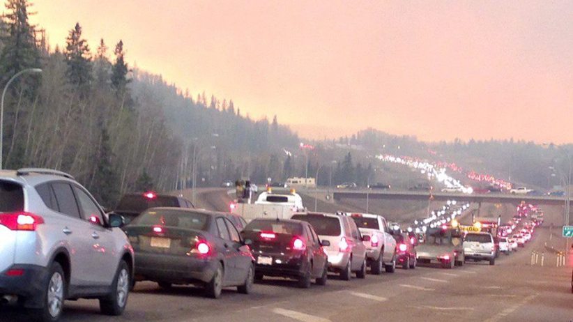 Smoke fills the air as cars line up on a road in Fort McMurray, Alberta on Tuesday May 3, 2016 in this image provide by radio station CAOS91.1. At least half of the city of Fort McMurray in northern Alberta was under an evacuation notice Tuesday as a wildfire whipped by winds engulfed homes and sent ash raining down on residents. (CP)