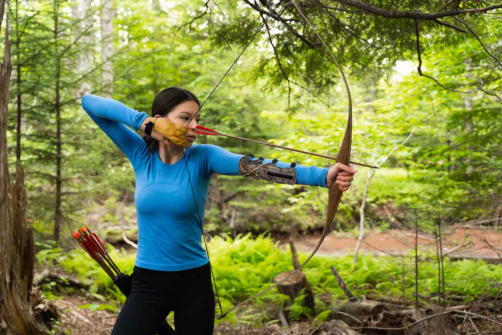 Young woman aiming bow and arrow