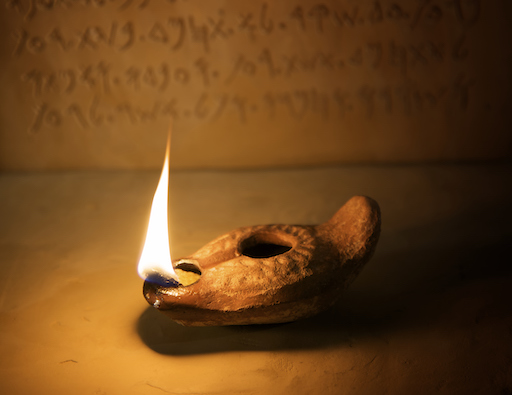 Oil Lamp with Ancient Inscription in Background