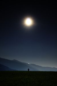 Person-standing-under-moon-at-night Person standing under moon at night