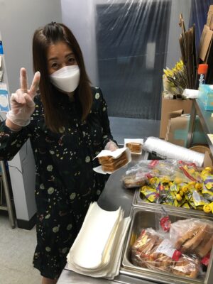 Woman holding sandwiches giving peace sign
