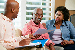 Financial Advisor Talking To Senior Couple At Home Showing Documents